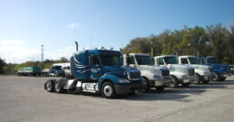 Sunbelt Transport flatbed trucks aligned in a parking lot under clear skies.