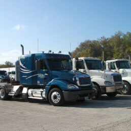 Sunbelt Transport flatbed trucks aligned in a parking lot under clear skies.