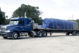 Sunbelt Transport truck carrying a load of concrete pipes secured with chains.