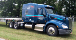 Side view of a flatbed truck in a parking lot, ready for a new load.