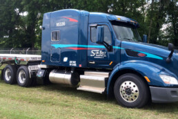 Side view of a flatbed truck in a parking lot, ready for a new load.