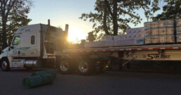 Sunbelt Transport flatbed truck loaded with construction materials, ready for delivery.